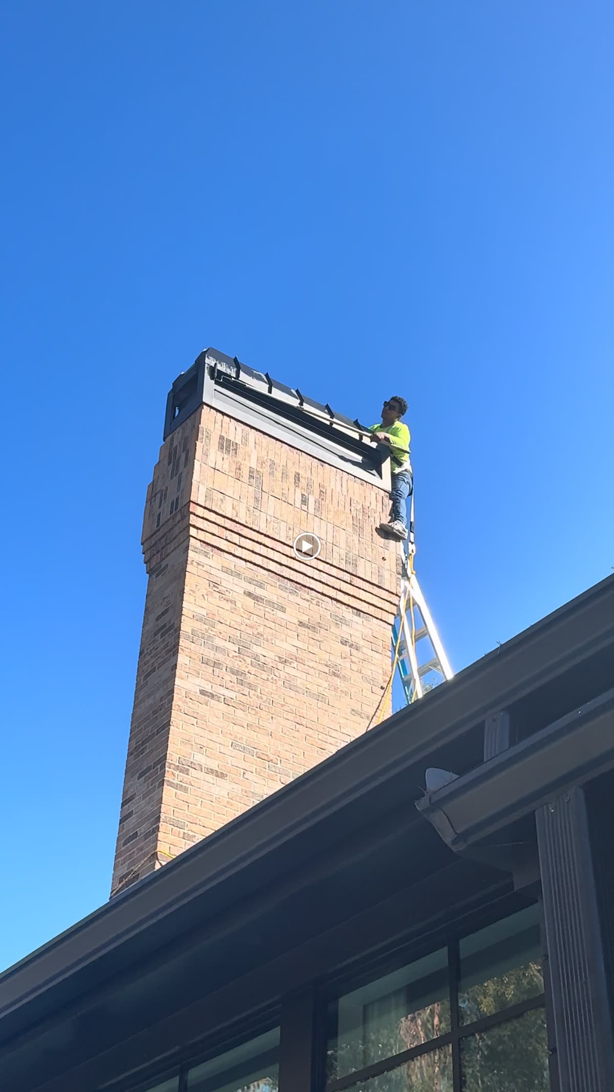 Worker atop a tall brick chimney